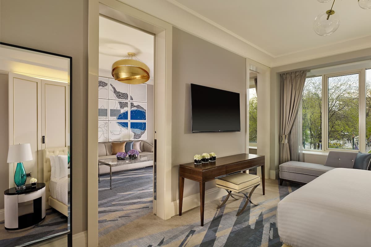 A hotel room with a bed, a desk, a TV, and a view of the outdoors.