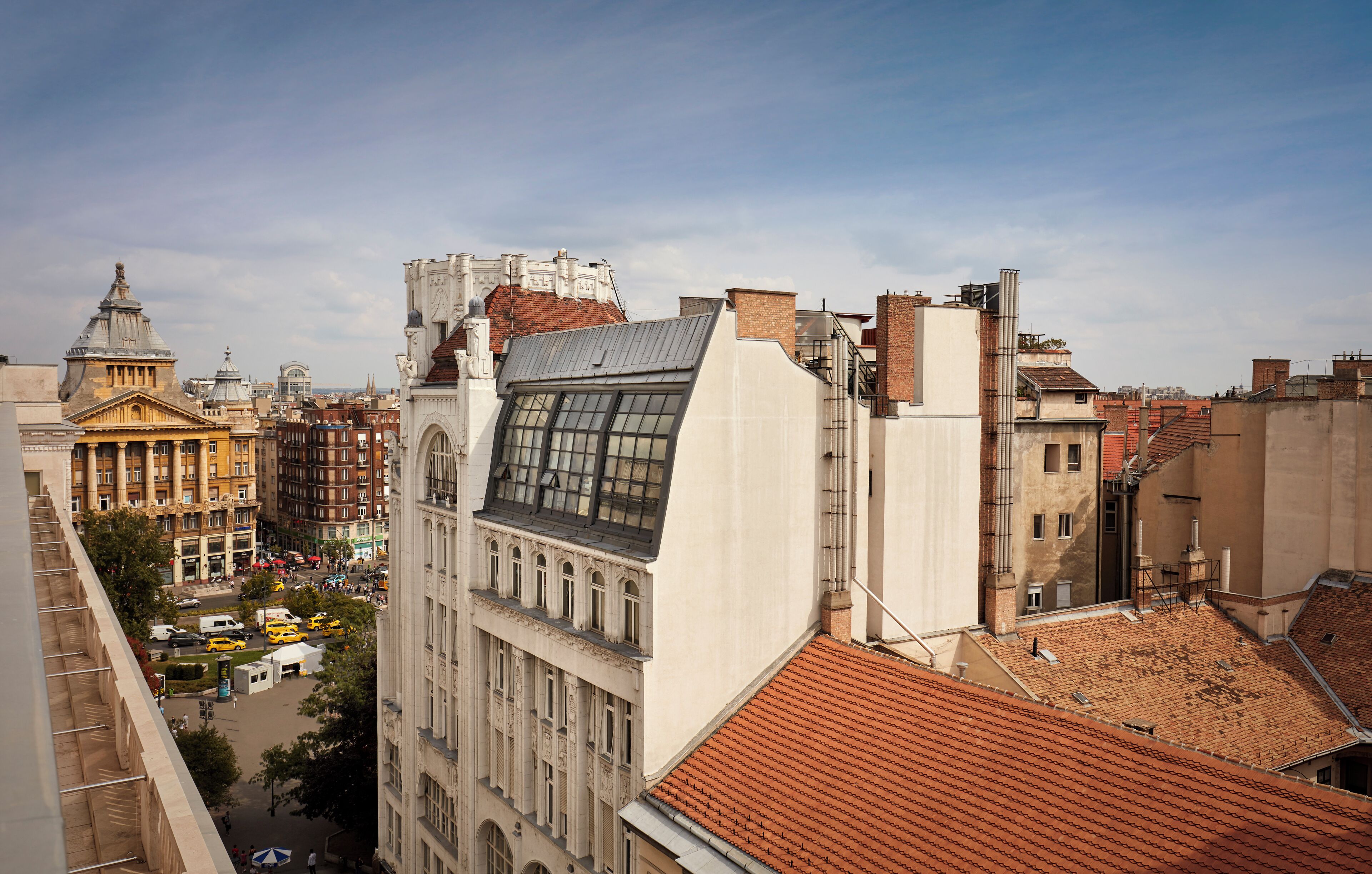 Un paisaje urbano con edificios históricos, incluyendo un edificio destacado con un amplio ventanal y un techo de tejas rojas.
