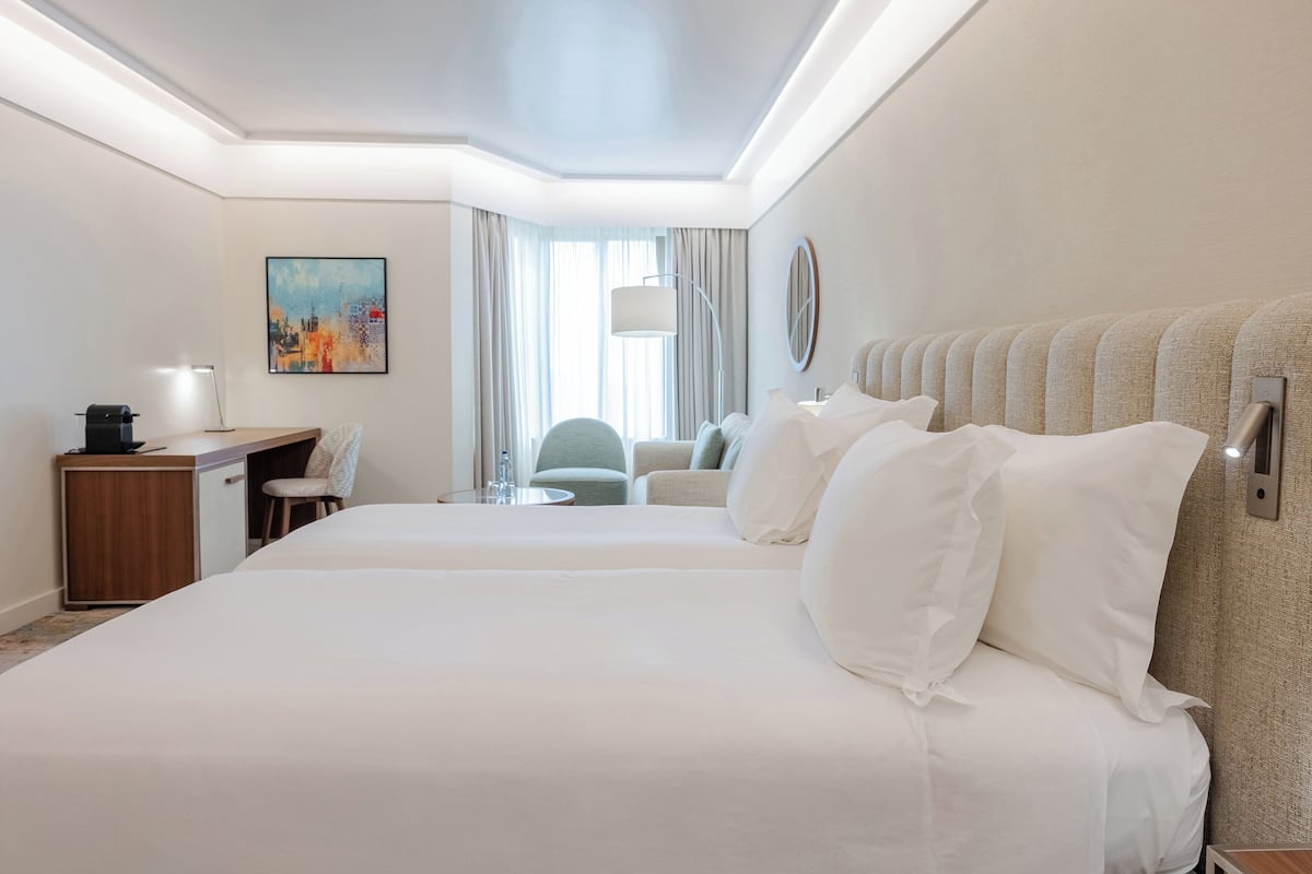 Habitación de hotel con una cama grande, un escritorio, una silla y un cuadro en la pared.