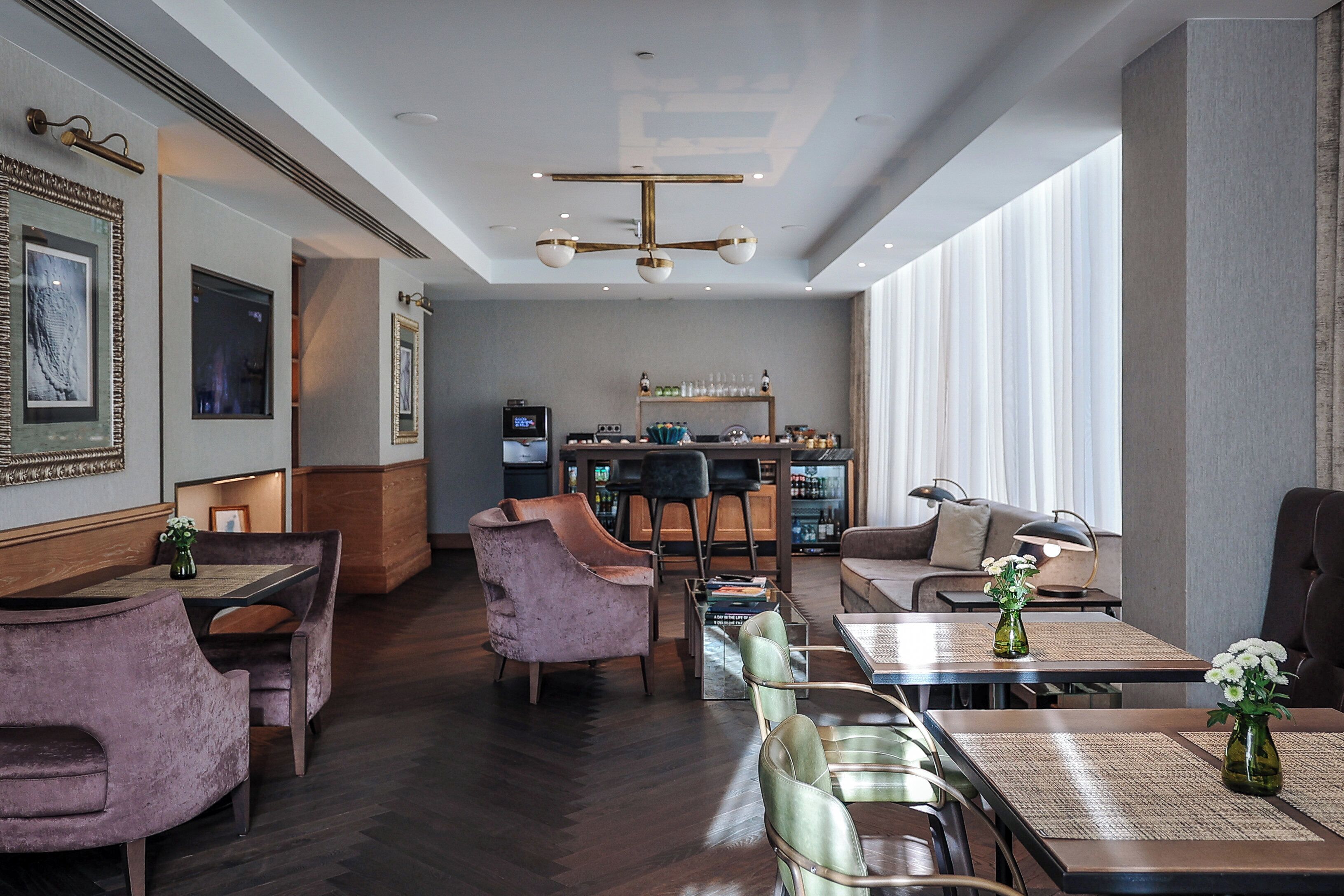 A modern hotel lobby with seating areas, a bar, and a reception desk.