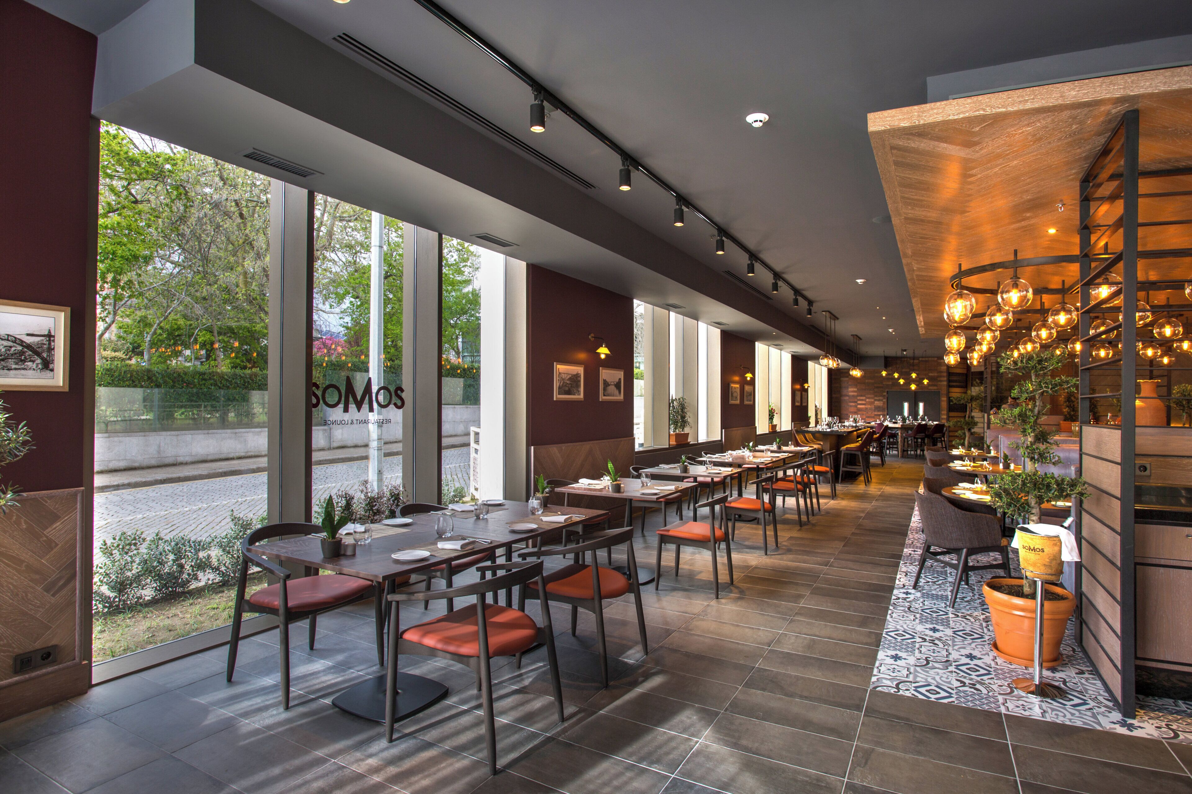 Un restaurante con mesas largas, sillas y vistas al exterior.