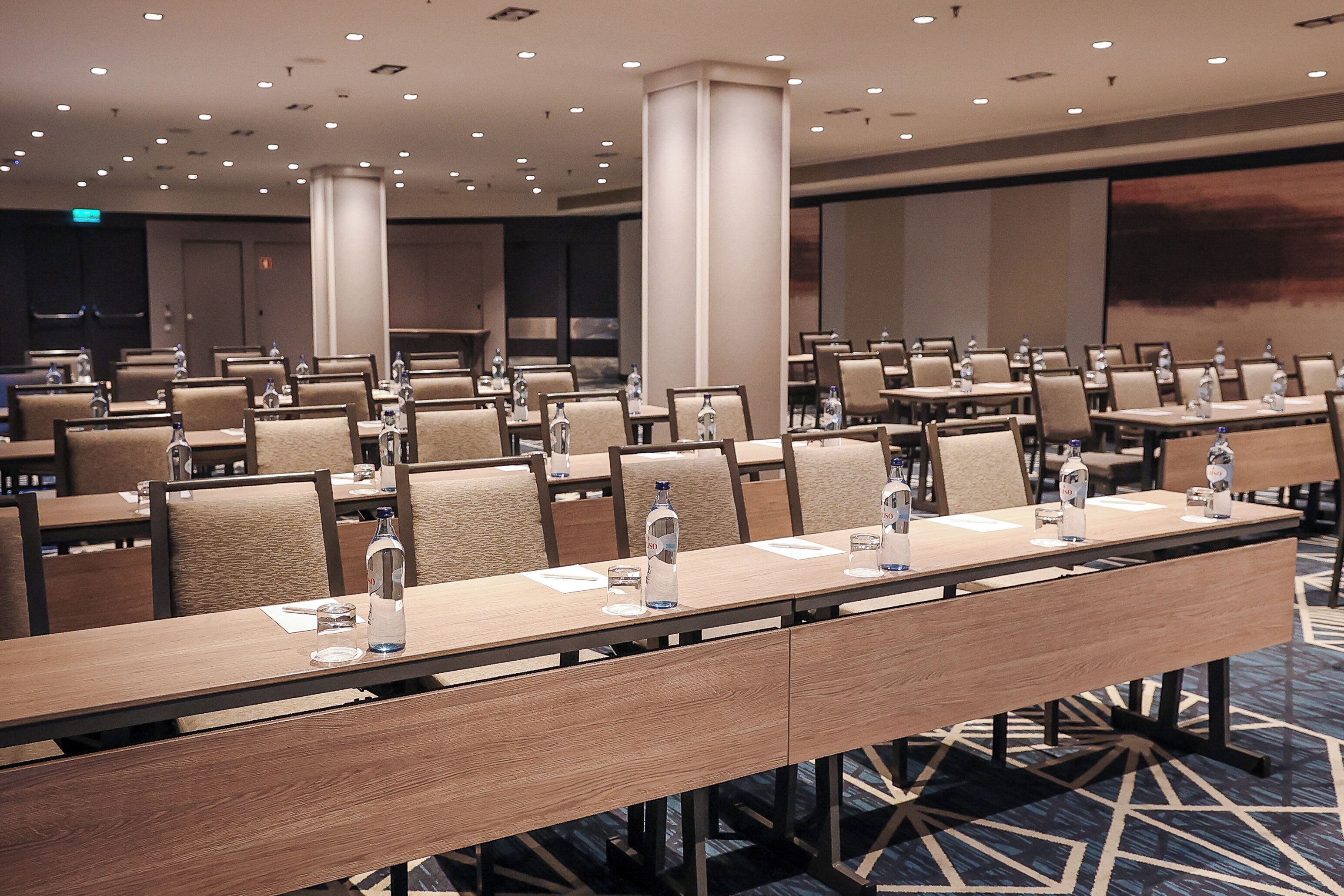 A conference room with multiple tables, chairs, and water bottles.