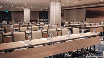A conference room with multiple tables, chairs, and water bottles.