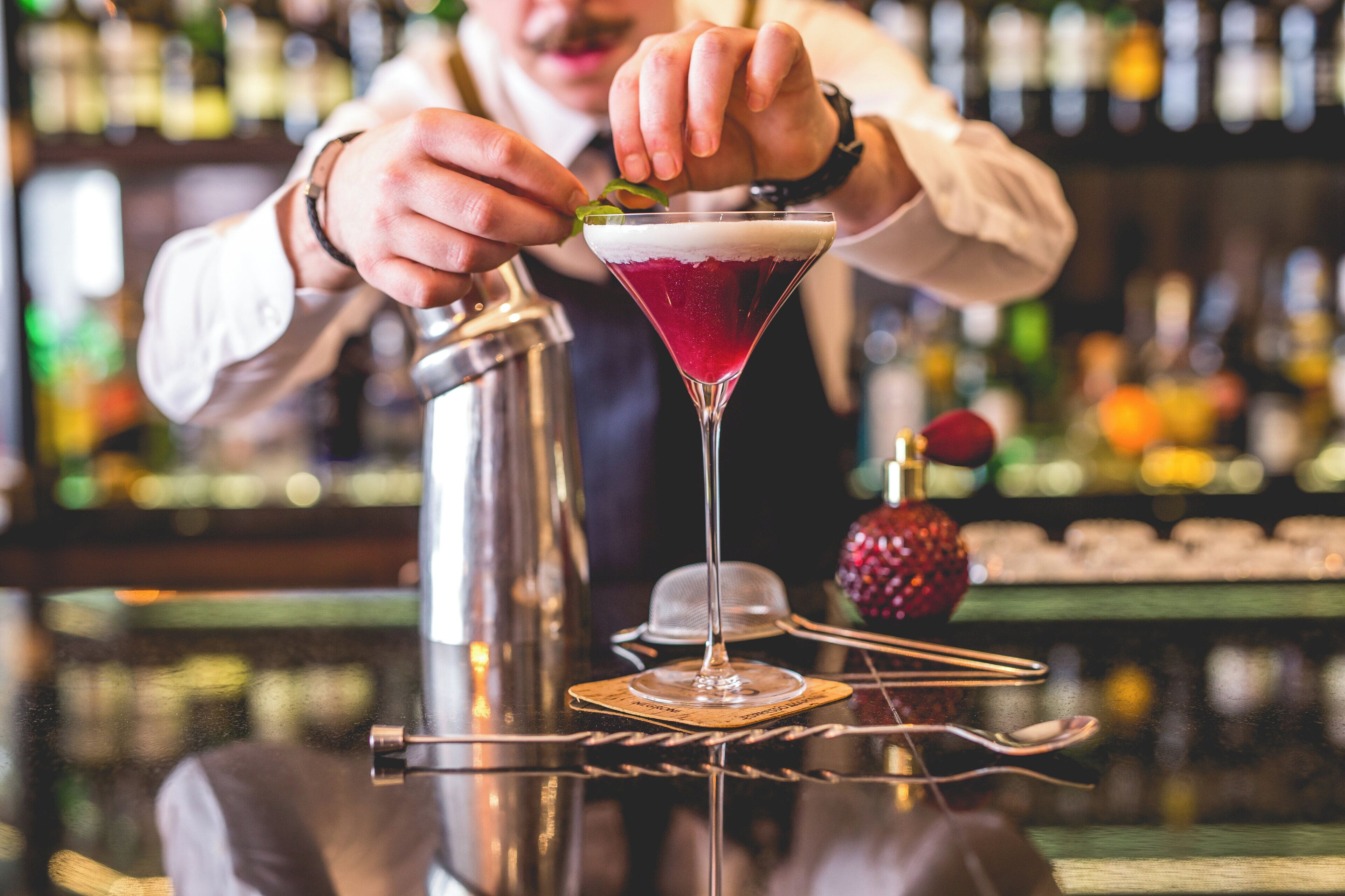 A bartender preparing a cocktail in a martini glass.