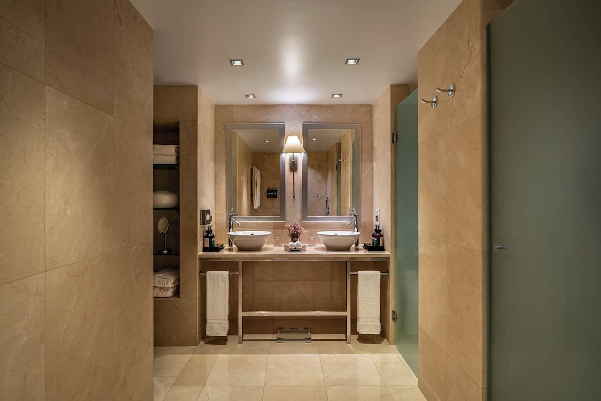 A bathroom with two sinks, a large mirror, and a towel rack.