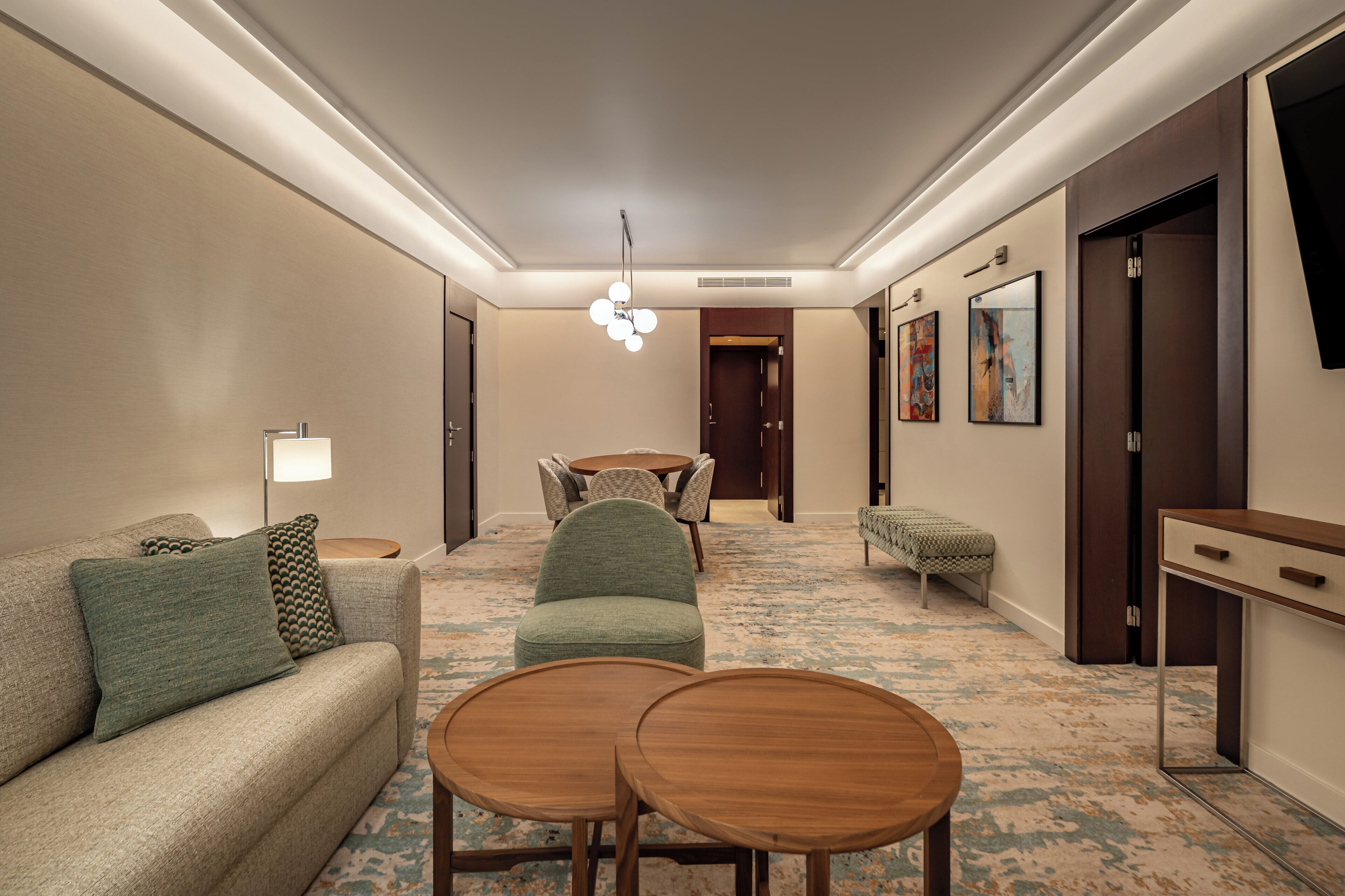 Un hall de hotel con un sofá, dos mesas redondas, una zona de comedor y obras de arte en las paredes.