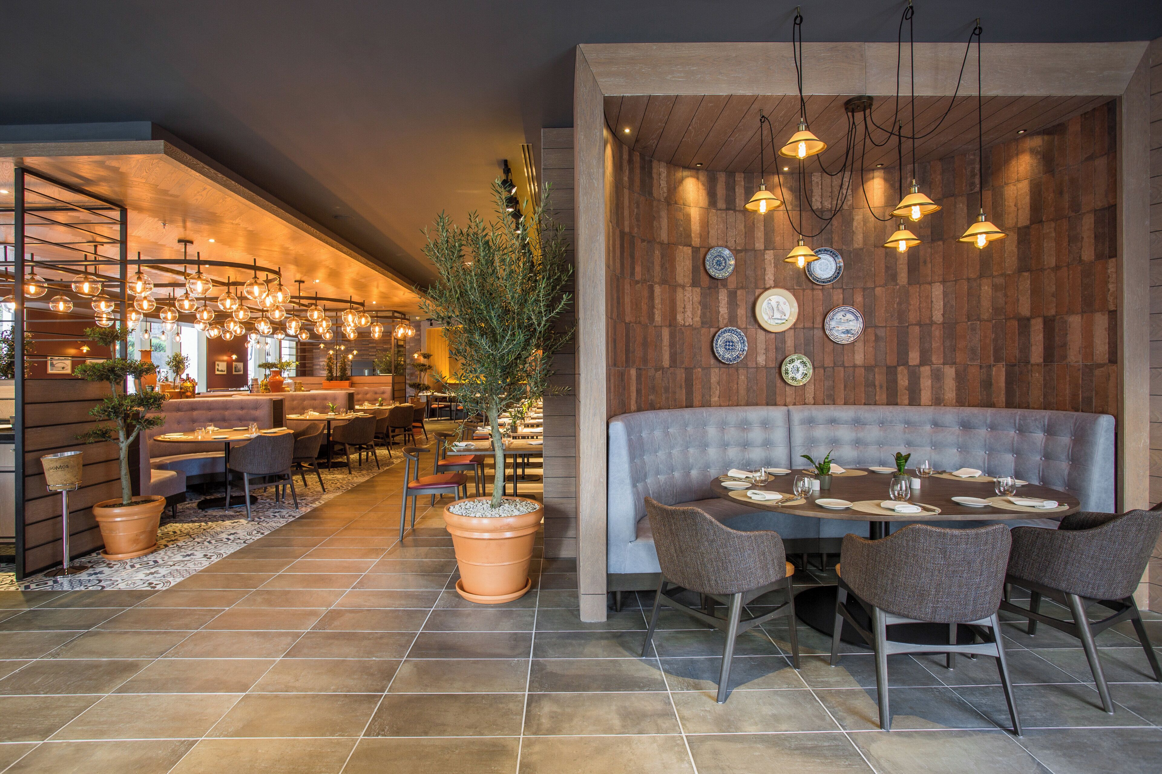 Un interior de restaurante con zona de bar, distribución de mesas y detalles decorativos.