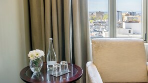 A hotel room with a view of the city, a round table with a vase of flowers, a bottle, and glasses. - Crowne Plaza Porto by IHG (Porto)