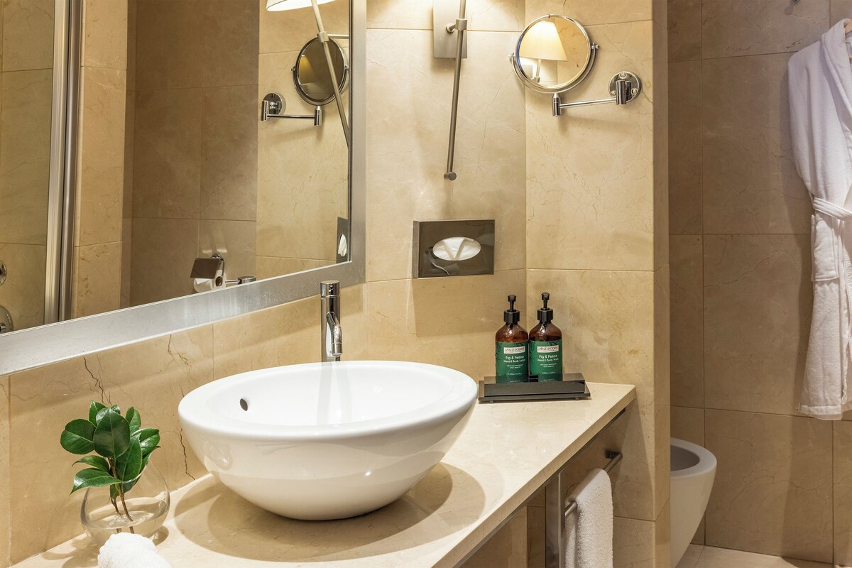 Un baño con un lavamanos grande y blanco, un espejo, un perchero y una bata colgada en la pared.