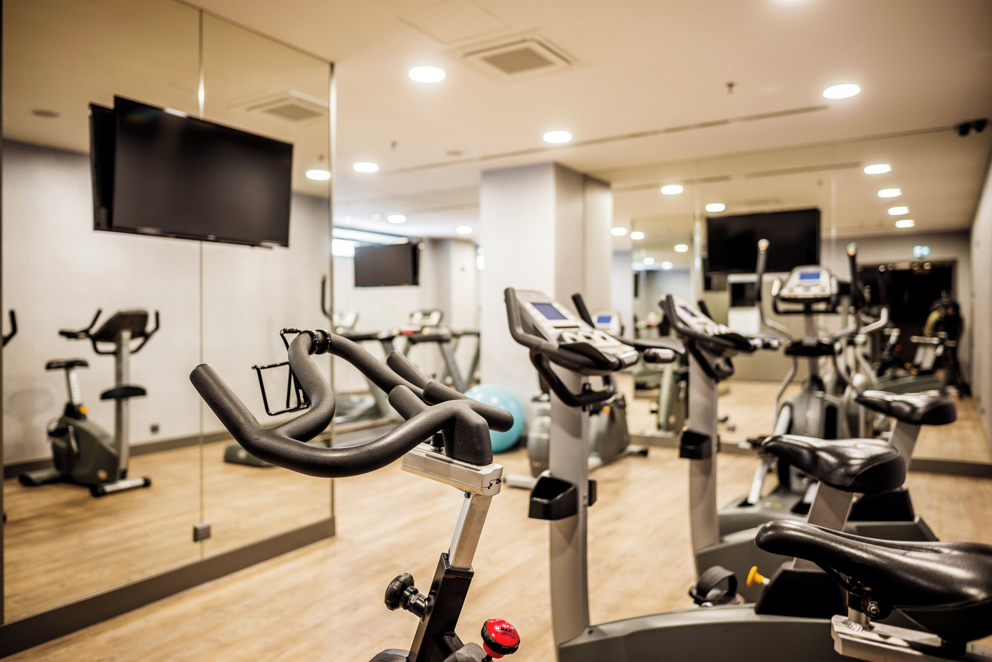 A gym with multiple exercise machines, including stationary bikes and treadmills, arranged in rows.