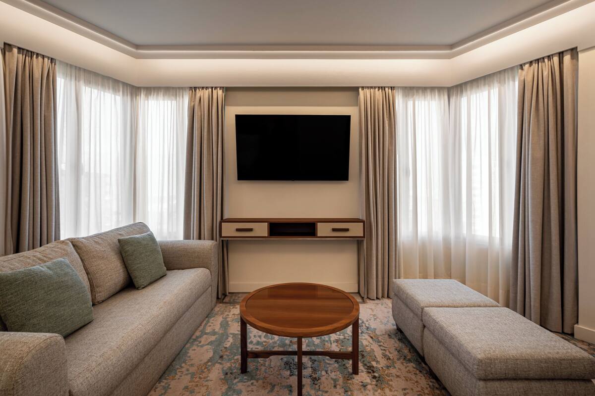 Una sala de estar moderna con un sofá, un reposapiés y una mesa de centro.