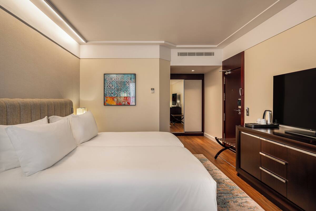 Habitación de hotel con una cama grande, un televisor de pantalla plana, un cuadro en la pared y un armario de madera.