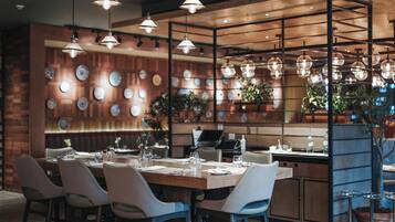 Un restaurante con pared de madera, luces colgantes y una variedad de platos exhibidos.