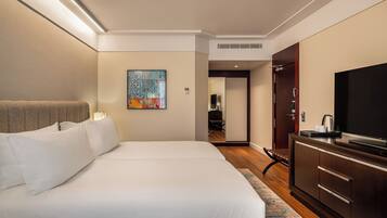 Habitación de hotel con una cama grande, un televisor de pantalla plana, un cuadro en la pared y una puerta que da al baño.