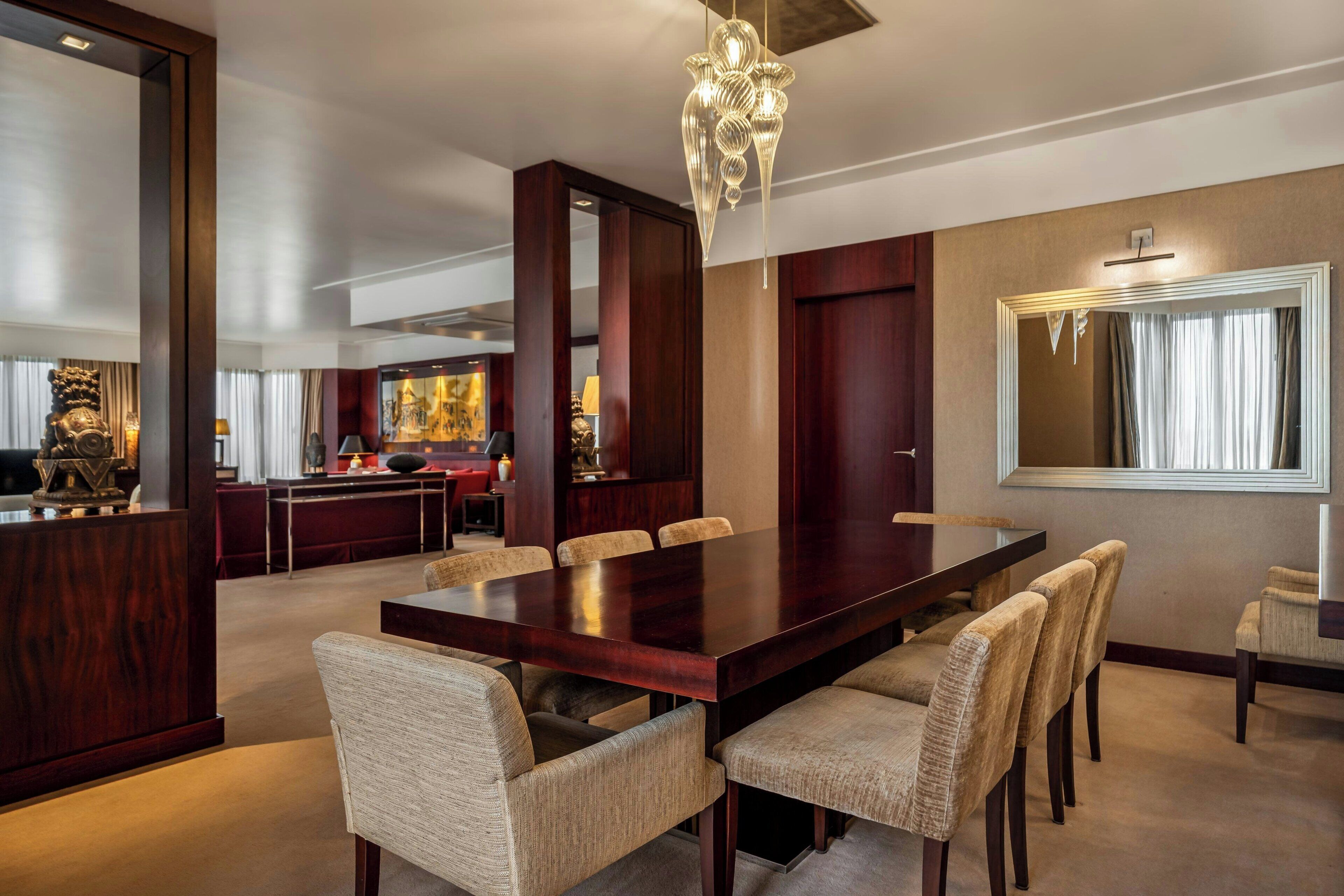 Un comedor amplio con una mesa larga, varias sillas y un candelabro.