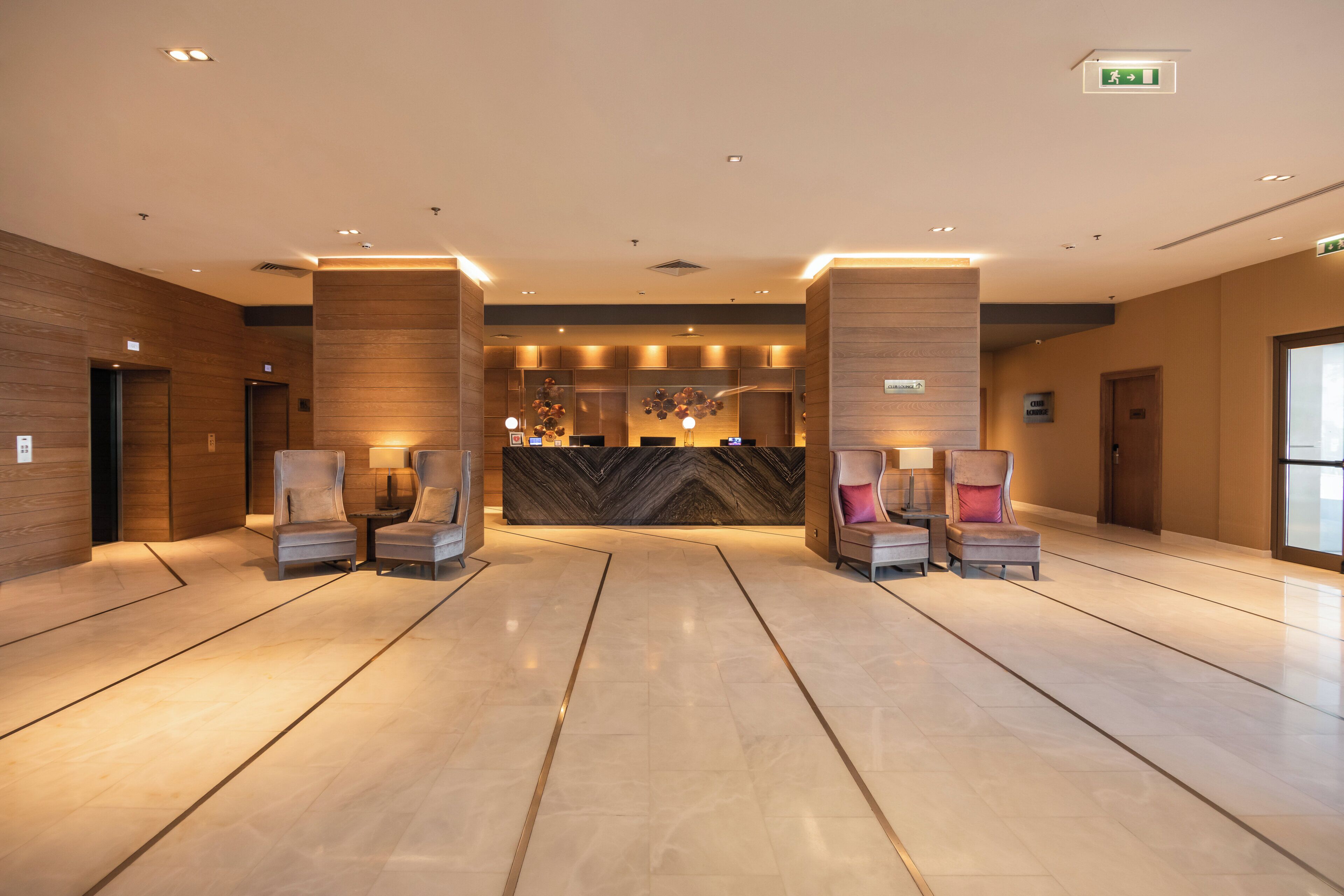 A hotel lobby with a reception desk, seating area, and a modern design.