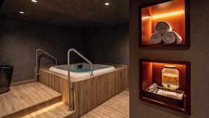 Un spa moderno con una bañera de madera, un juego de escalones y un estante con toallas y un tarro de sales de baño.
