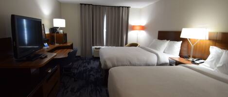 Habitación de hotel con dos camas, un escritorio con televisor y dos lámparas de noche.