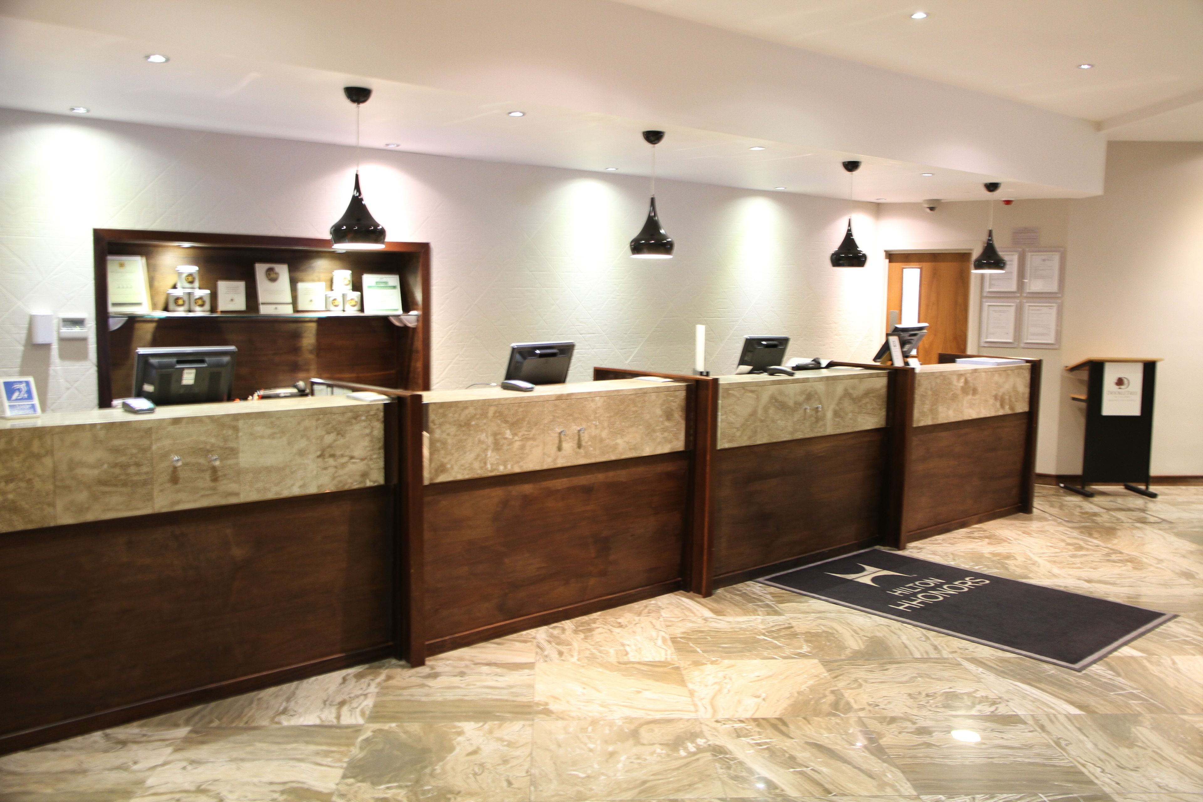 A reception desk with a marble floor, wooden paneling, and pendant lighting.