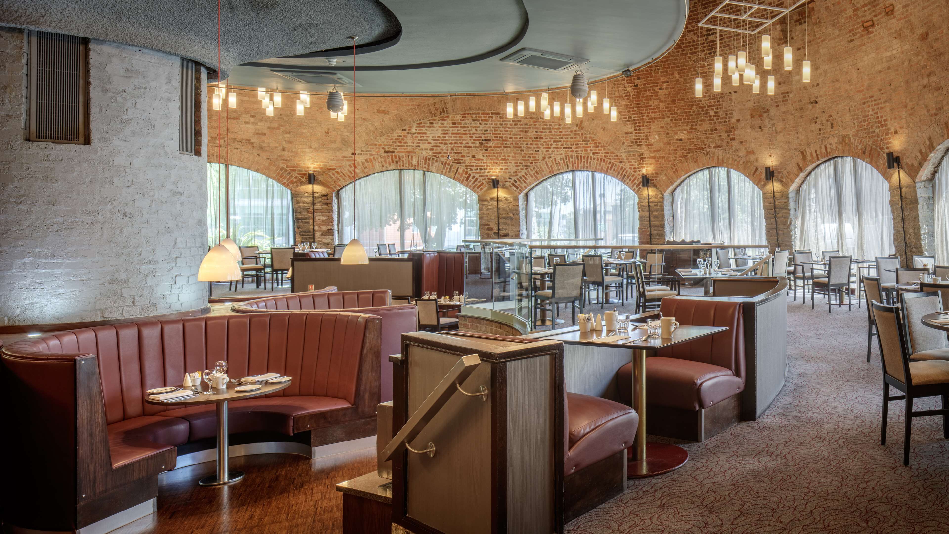 A restaurant with brick walls, arched windows, and modern lighting.