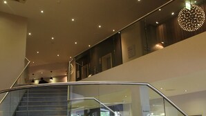 A modern interior with a glass railing staircase, a circular light fixture, and a reception area. - Doubletree by Hilton Bristol (Bristol)