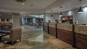 A hotel lobby with a reception desk, seating area, and a staircase leading to another level. - Doubletree by Hilton Bristol (Bristol)