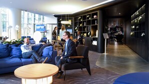 Una hall moderna con un divano blu, un tavolino di legno e una reception.