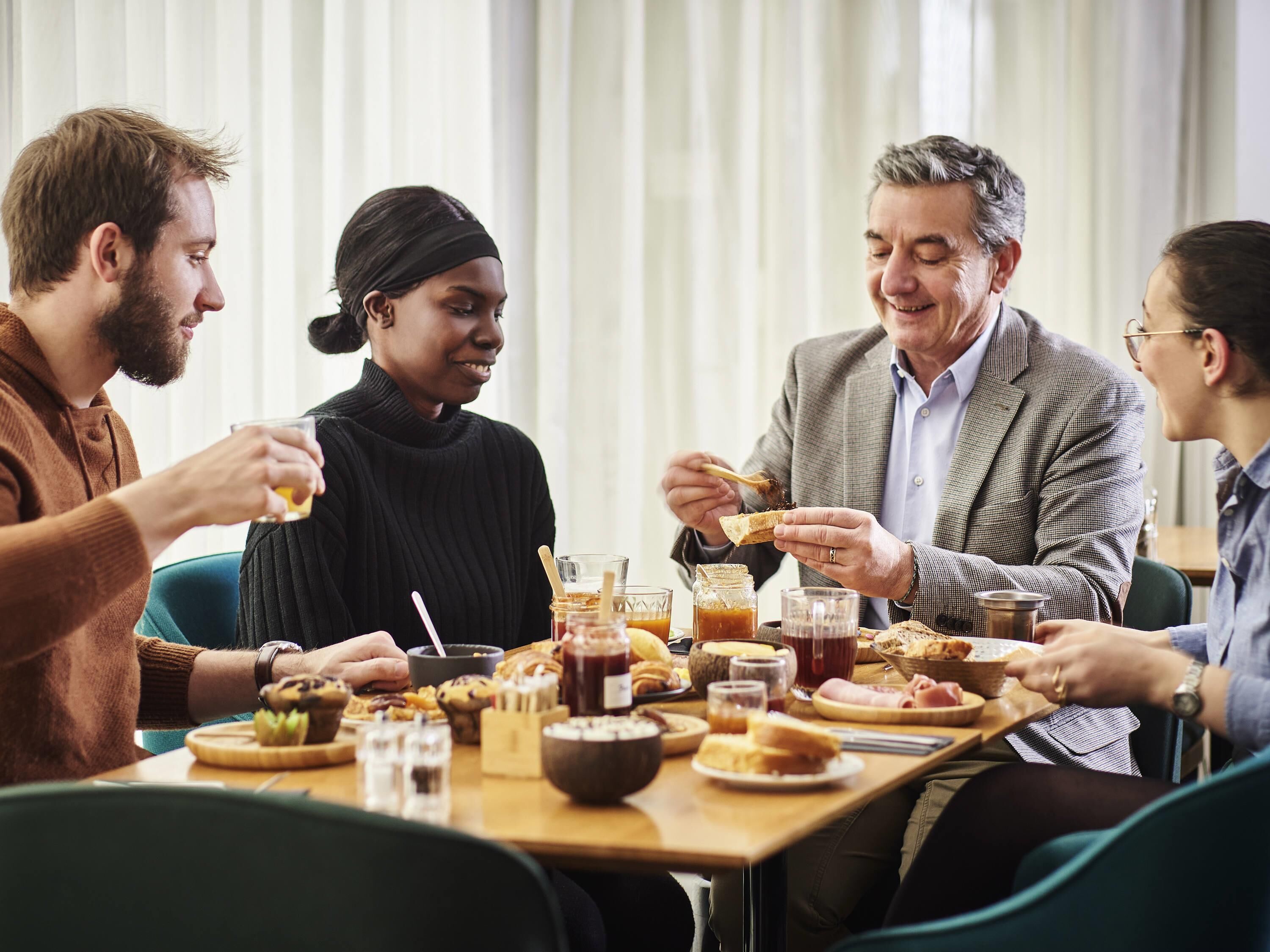 Un grupo de personas cenando en una mesa con diversos platos y bebidas.