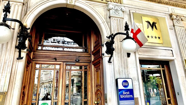 L’entrée de l’hôtel Alberghetto Moderno Verdi présente un style architectural classique, avec des décorations raffinées et une enseigne indiquant qu’il s’agit d’un hôtel Best Western.