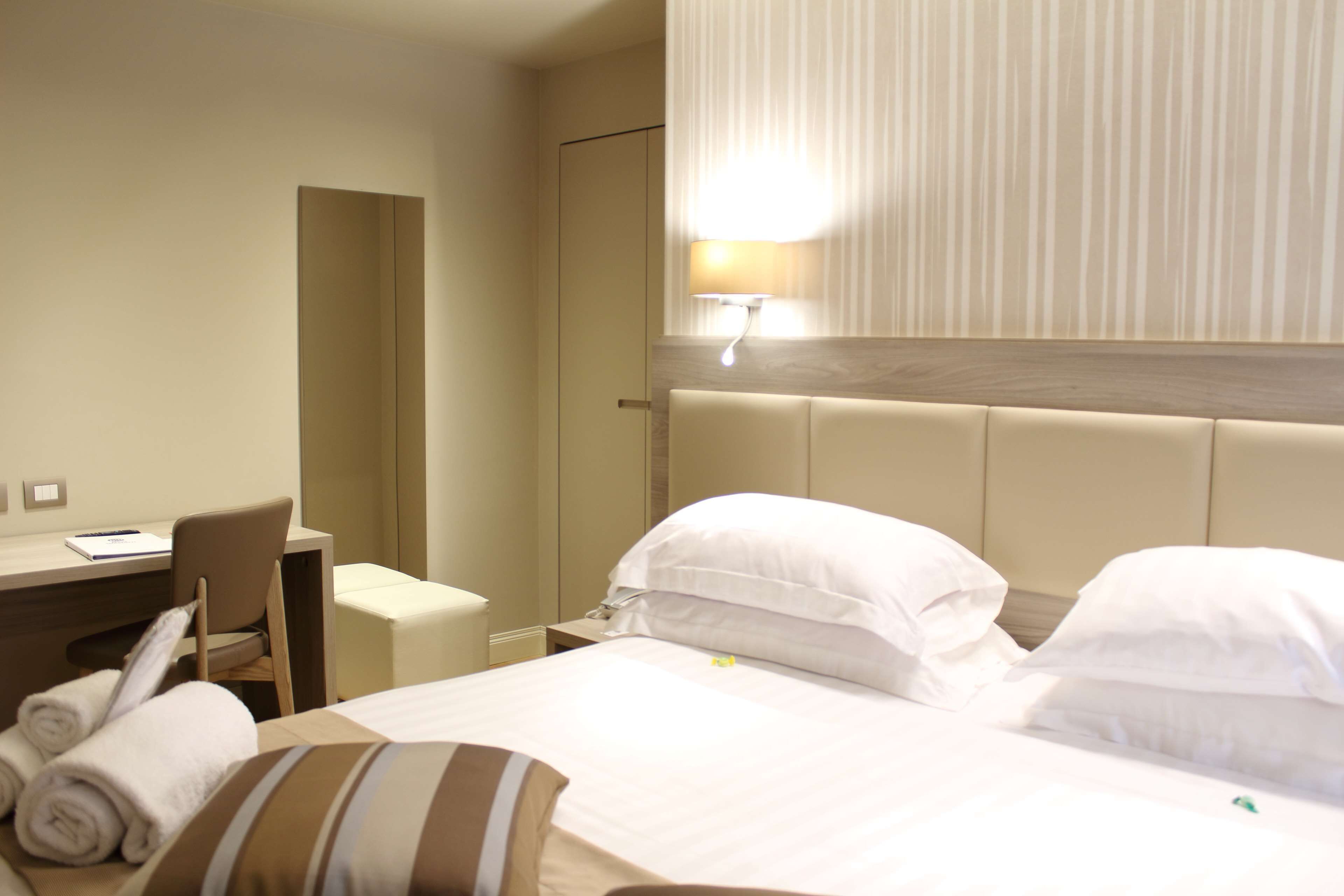 A hotel room with a bed, a desk, a chair, and a nightstand.