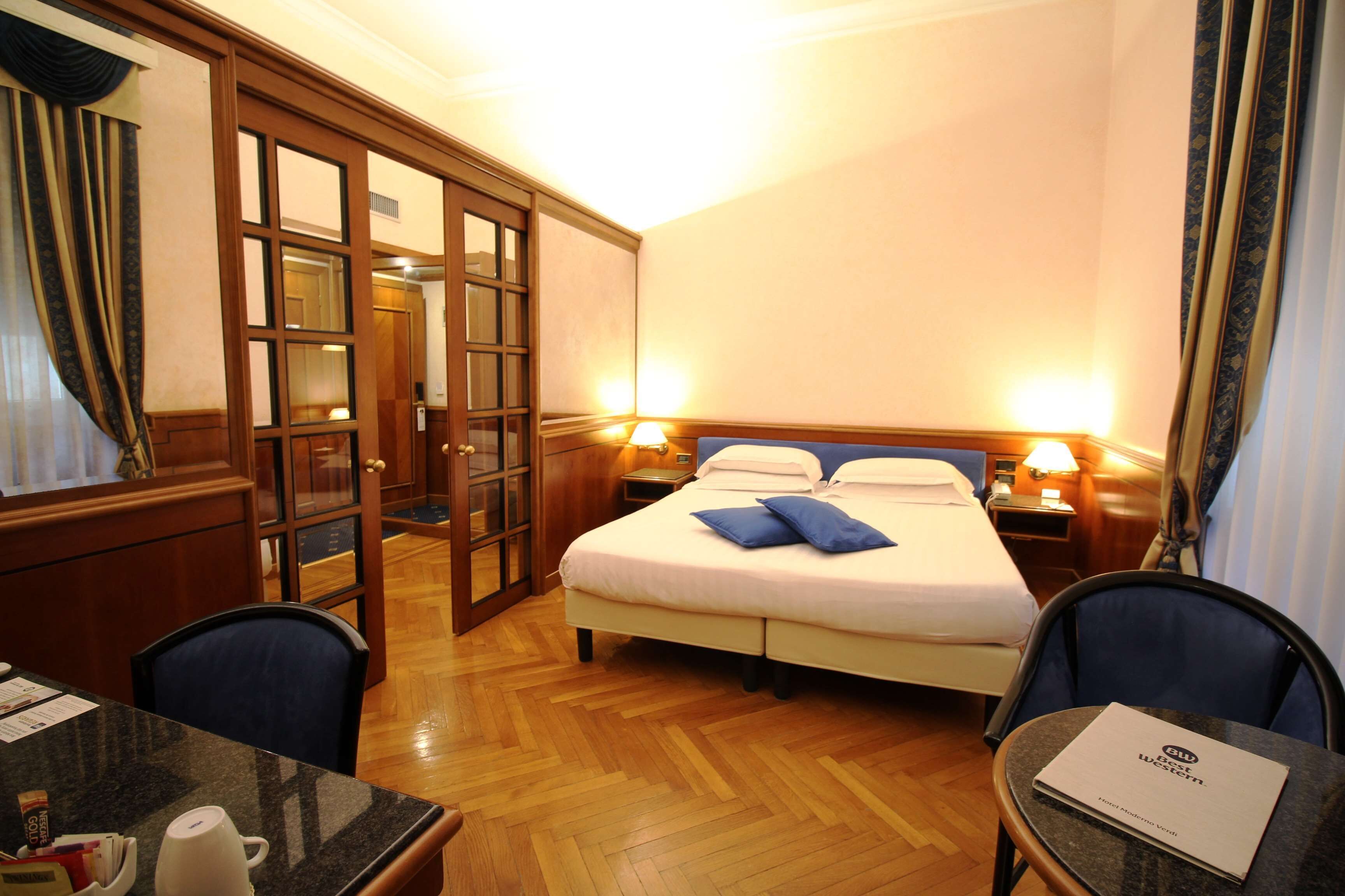 Ein Hotelzimmer mit Bett, Nachttischen, Schreibtisch und Stuhl.