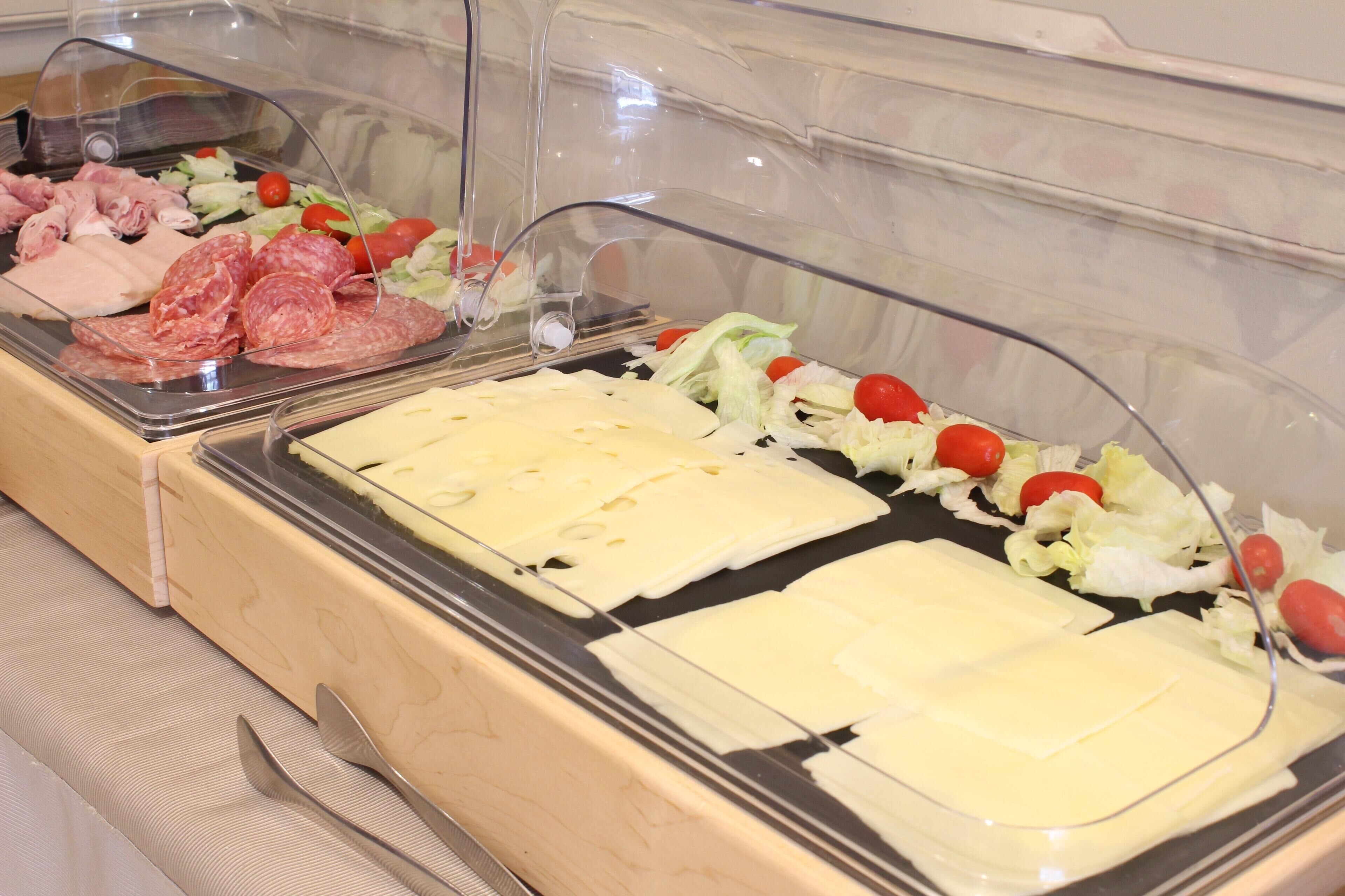 Een buffet met diverse vleessoorten, kaas en verse groenten.