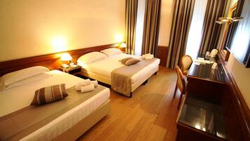 A hotel room with two beds, a desk, and a chair.