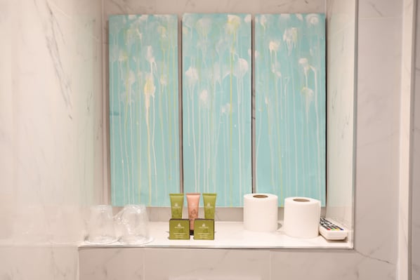 A bathroom with a marble wall, a shelf with toiletries, and a blue decorative panel.