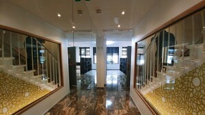 Un pasillo con piso de mármol, barandales de vidrio y una escalera con un revestimiento mural decorado.