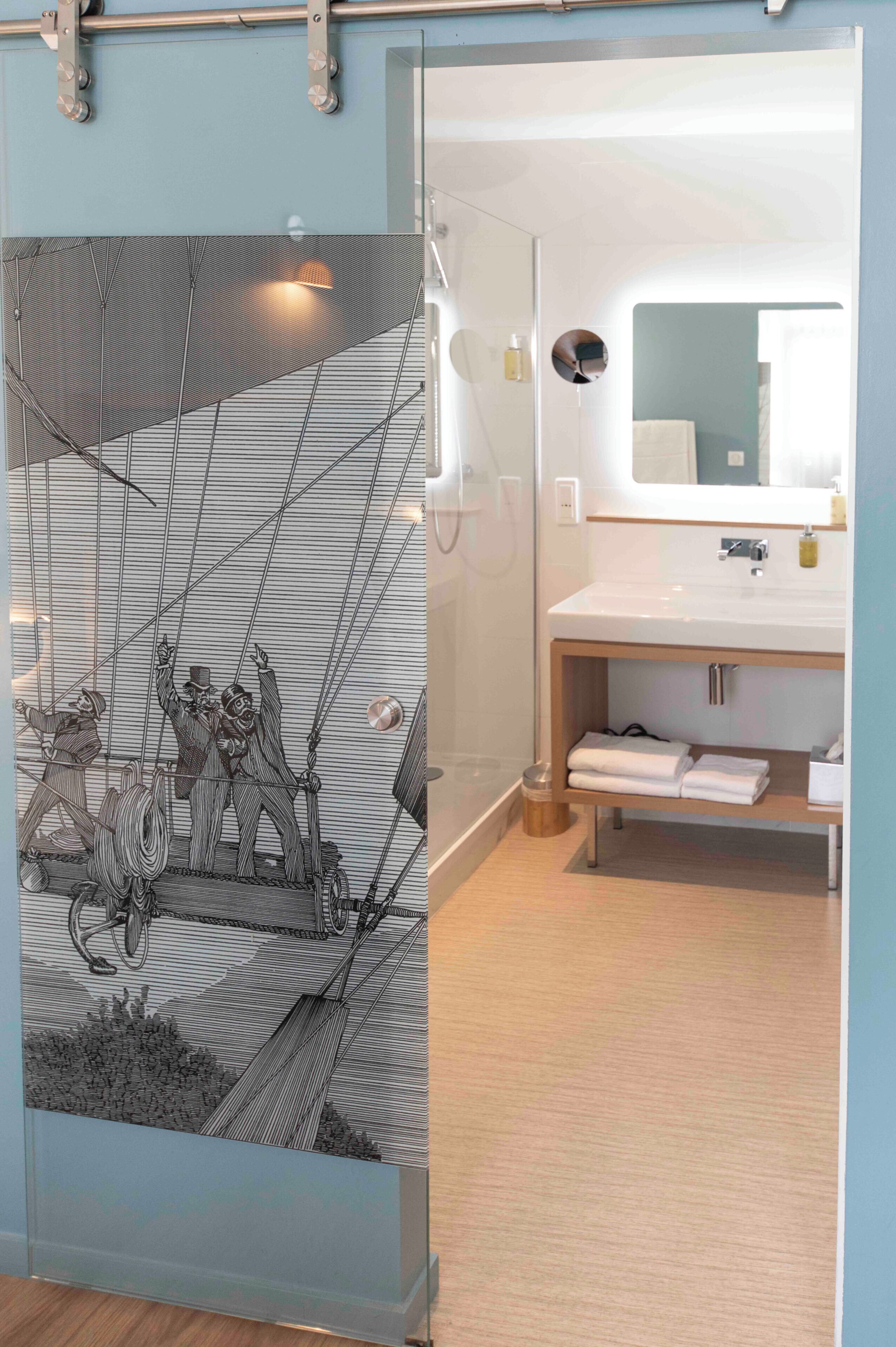 A modern bathroom with a large mirror, a white sink, and a towel rack.