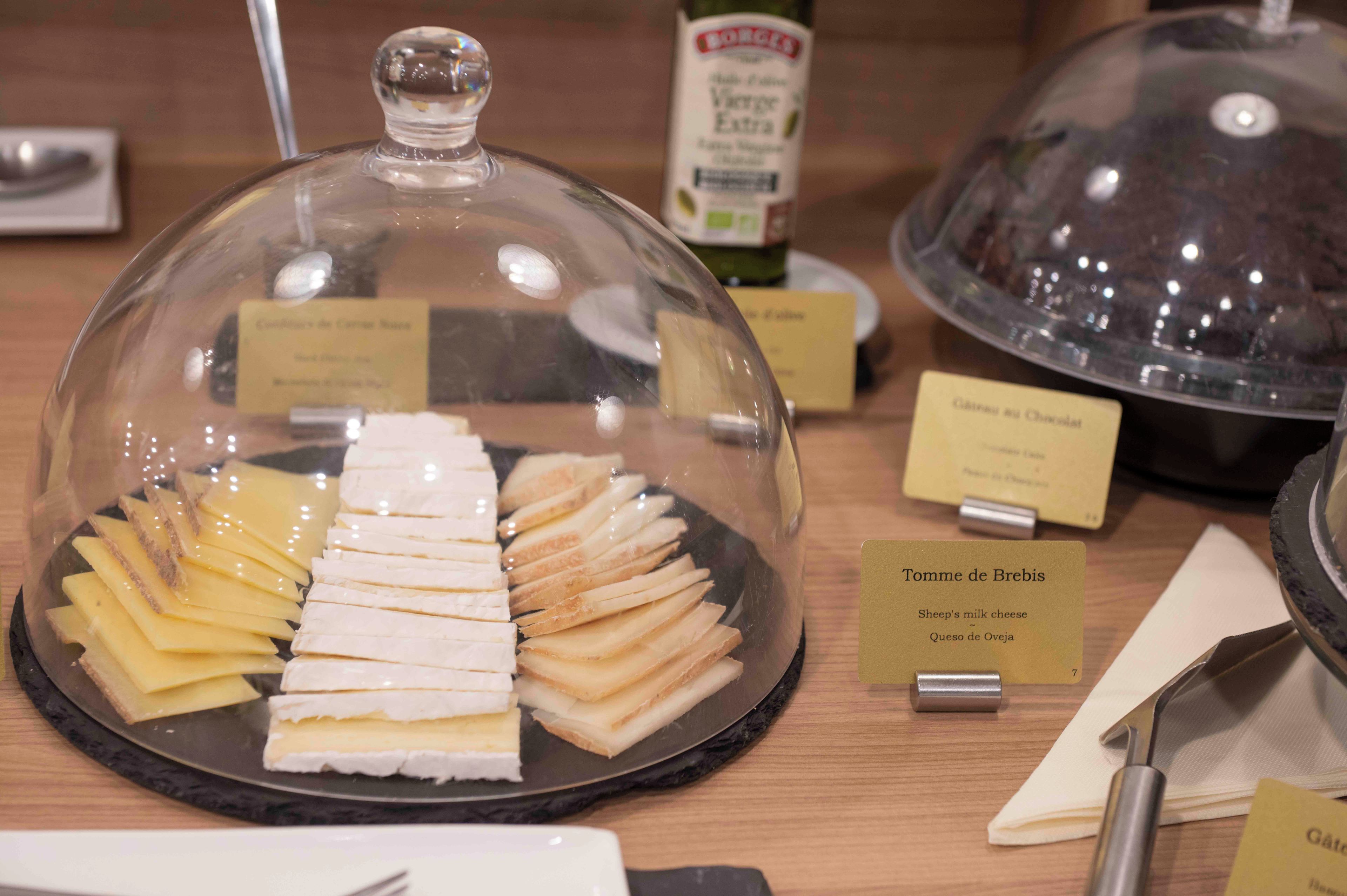 A cheese display with labels for Tomme de Brebis and Gouda.