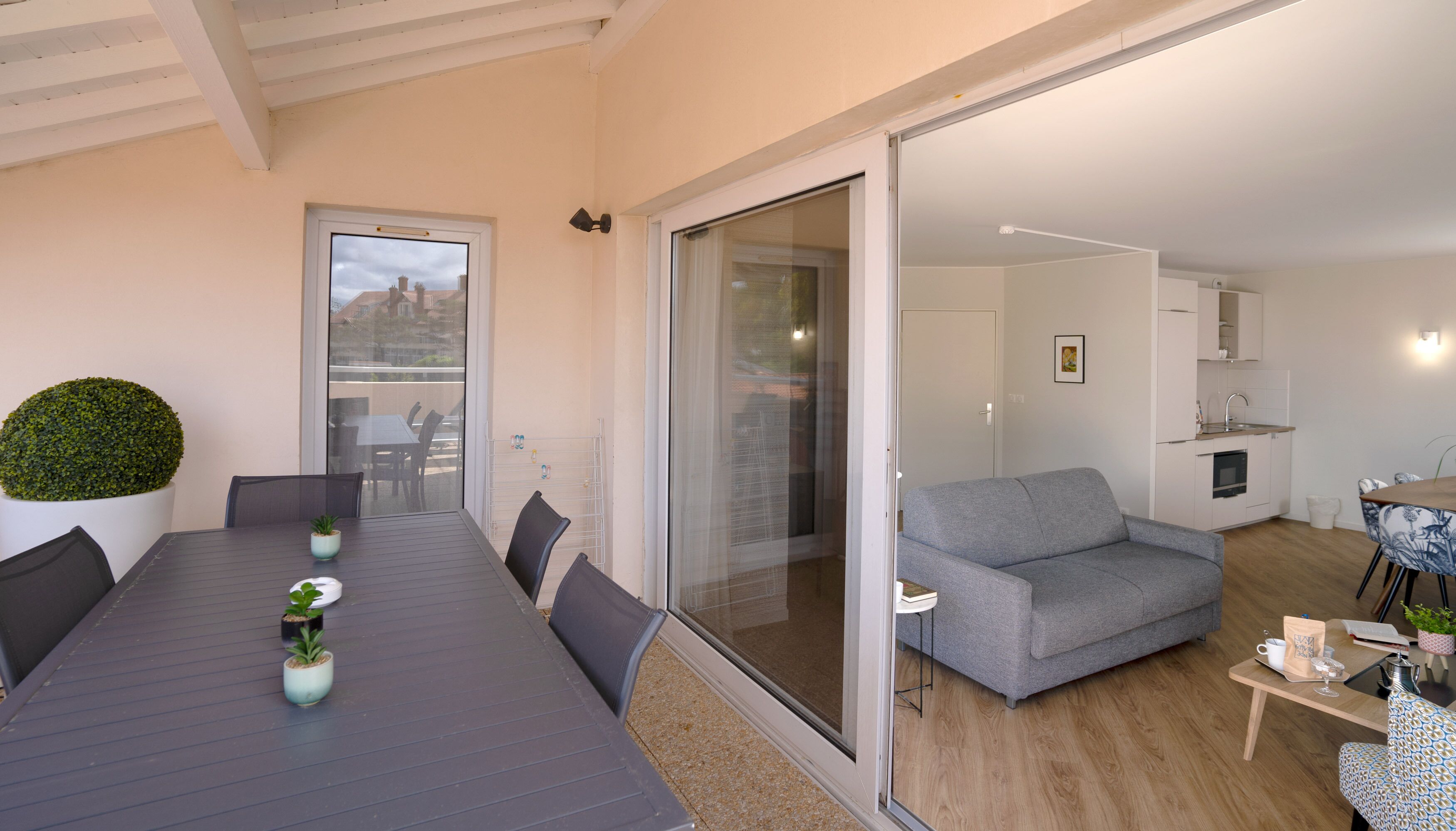 A modern living space with a dining area, a grey sofa, and a kitchen.