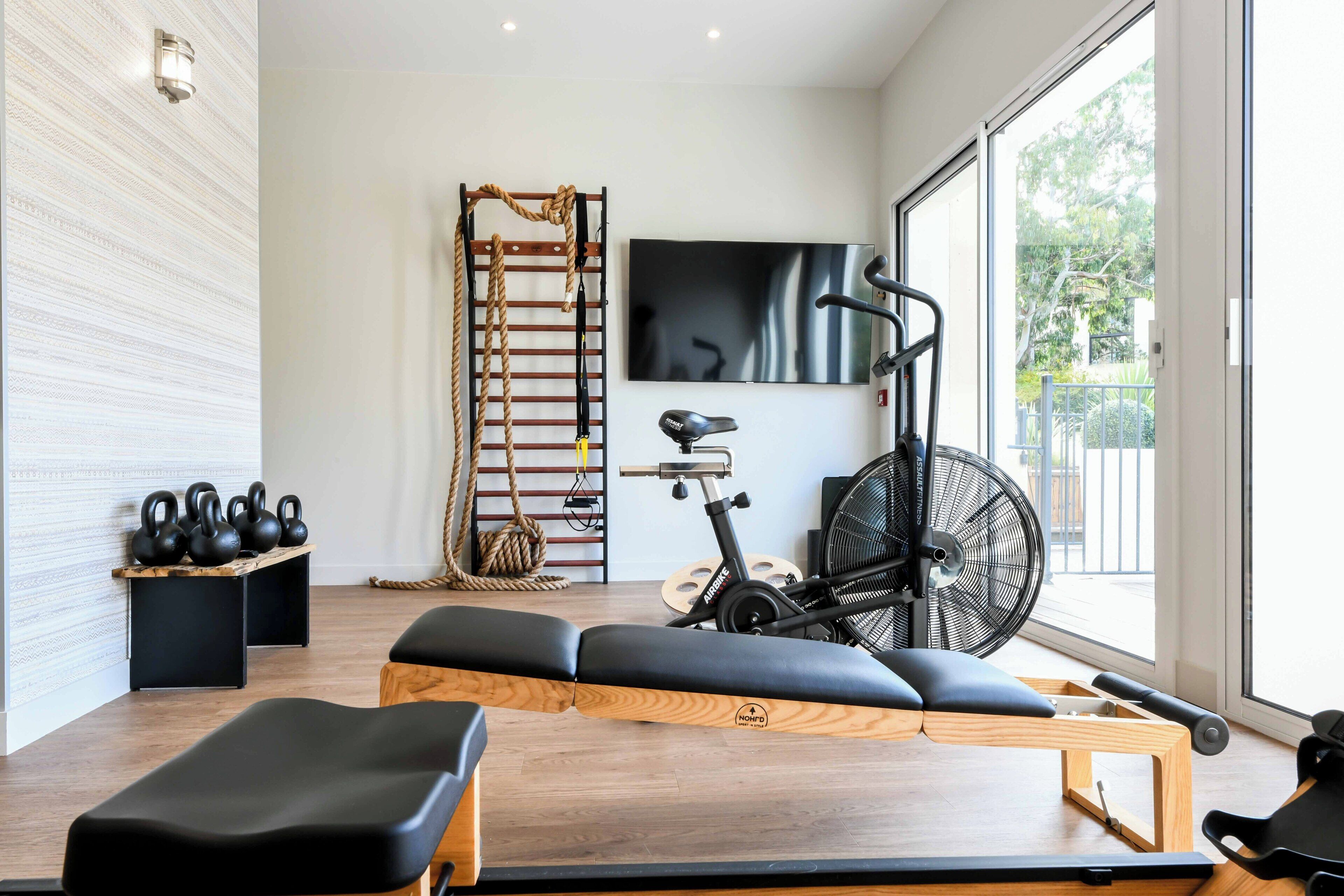 Een moderne sportschool met fitnessapparatuur, een televisie en een groot raam.