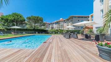 Relax by the pool surrounded by lush greenery and comfortable lounge chairs.