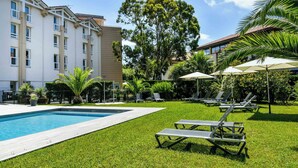 A hotel pool area with a wooden deck, lounge chairs, and umbrellas. - Hôtel Jules Verne Biarritz (Biarritz)