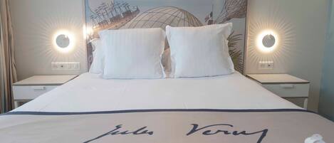 A hotel room with a large bed, two bedside tables, and a headboard with a mural.