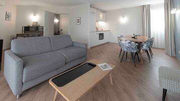 Un salon moderne avec un canapé gris, une table basse en bois et un coin repas doté de chaises à motifs.