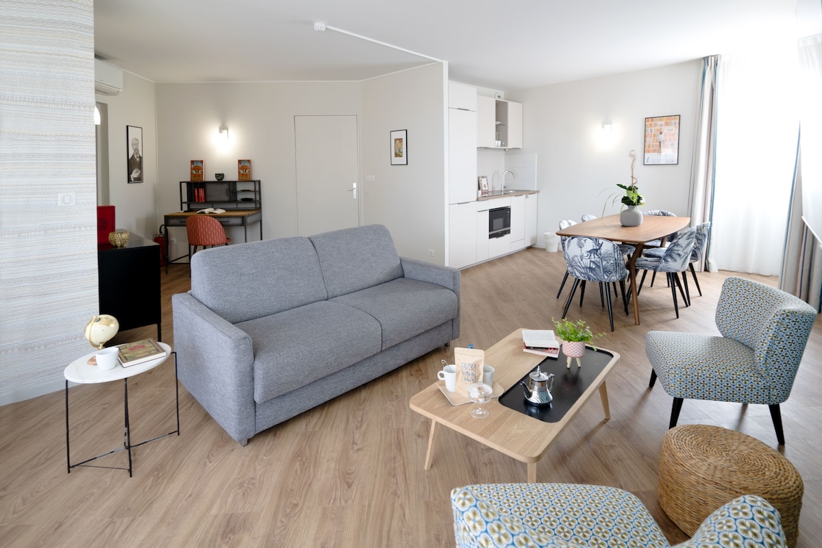 En moderne stue med en grå sofa, et sofabord og mønstrede stole.