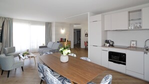 A modern apartment with a dining area, kitchen, and living room. - Hôtel Jules Verne Biarritz (Biarritz)