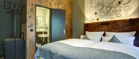 A modern bedroom with a large bed, a wooden headboard, and a wall-mounted light fixture.