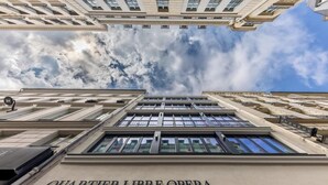 The exterior of the Quartier Libre Opera building with a clear sky and clouds above. - Le Pera (Paris)