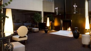 A spacious lobby with a fireplace, seating areas, and decorative plants. - Le Pera (Paris)