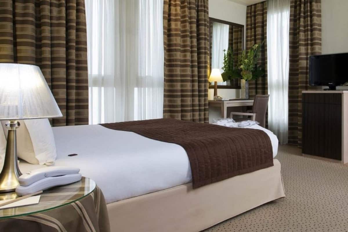 Une chambre d’hôtel comprenant un lit, un bureau avec une lampe, une télévision et une salle de bain.