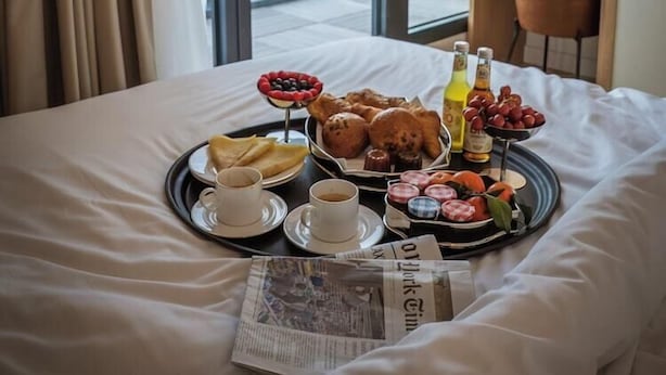 A hotel room with a bed, a tray of breakfast items, and a newspaper. - Le Pera (Paris)